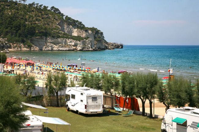Spiaggia con camper, ombrelloni e mare.