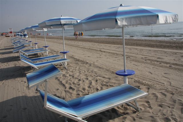 Ombrelloni e lettini blu su una spiaggia sabbiosa.