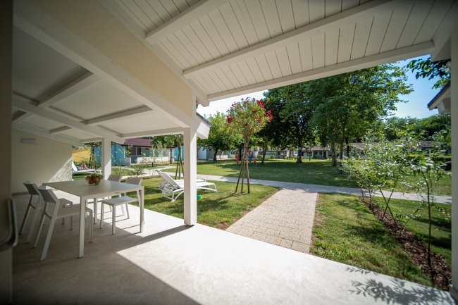 Veranda con tavolo, sdraio e giardino curato.