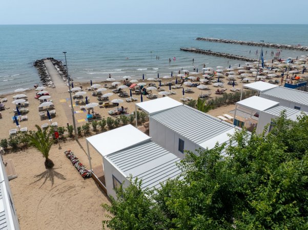 Spiaggia con ombrelloni e passerella verso il mare.