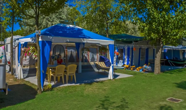 Una tenda blu con sedie gialle su erba.