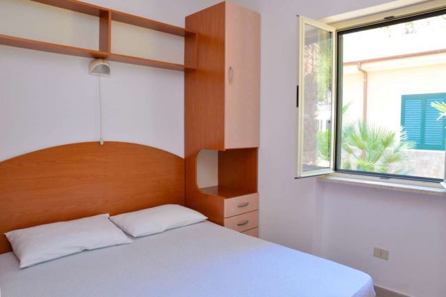 Camera da letto con finestra e letto matrimoniale.