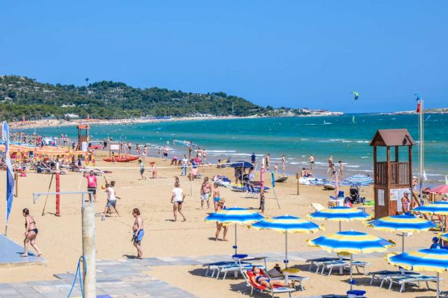 Spiaggia animata con ombrelloni gialli e blu.