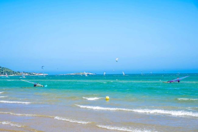 Mare con vele e kite a distanza.