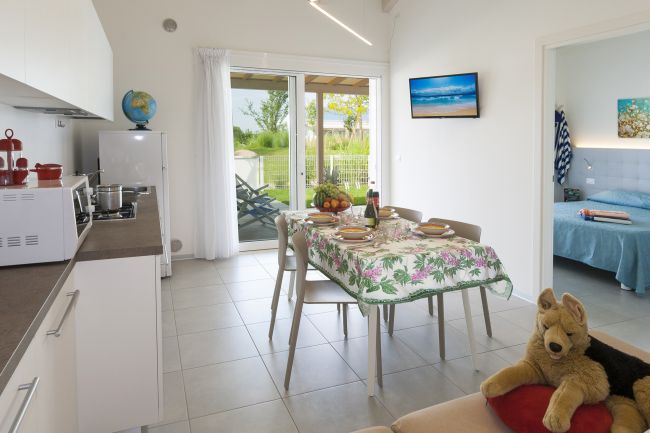 Cucina moderna con tavolo apparecchiato e accesso al giardino.