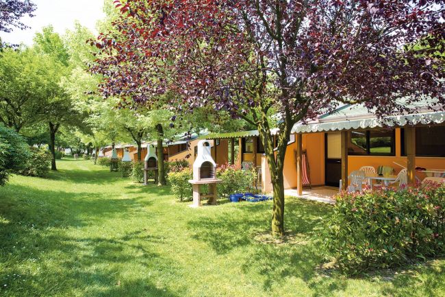 Giardino con barbecue in muratura e casette arancioni.