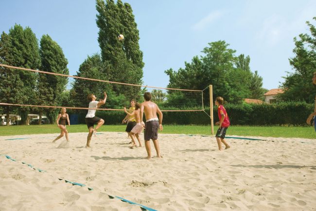Sei persone giocano a beach volley.