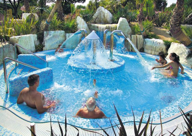 Persone si rilassano in una piscina con getti d'acqua.