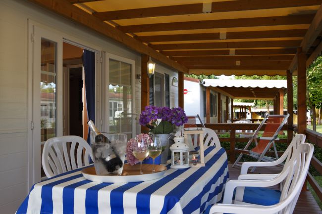 Veranda coperta con tavolo e sedie bianche.