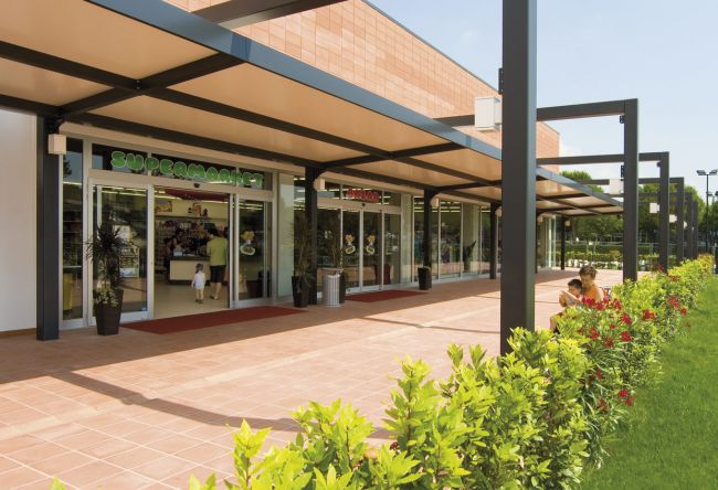 Ingresso di un supermercato con un giardino fiorito.