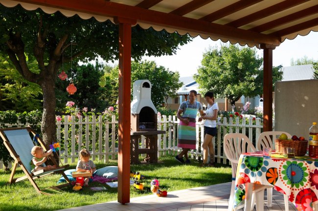 Giardino con tavolo apparecchiato e bambini che giocano.