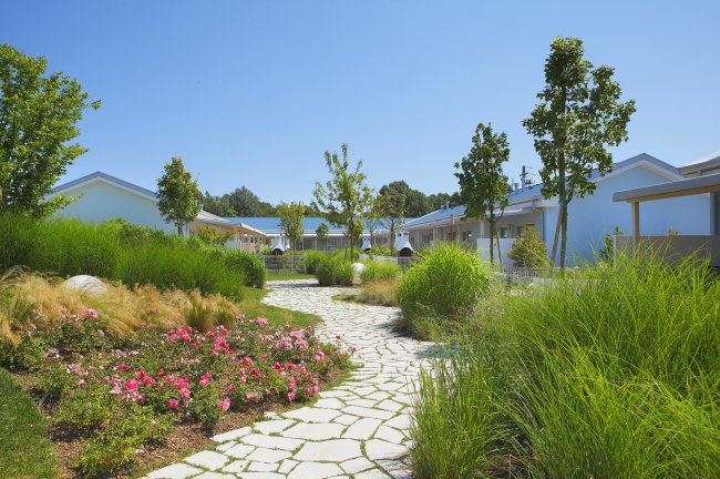 Un giardino curato con vialetti lastricati e casette bianche.